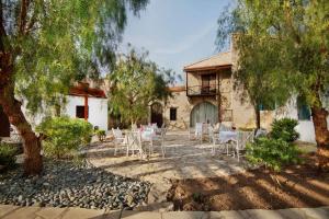 a patio with tables and chairs in front of a building at Meleni Cottage Houses in Parekklisha