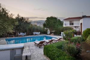 a swimming pool in a yard with chairs and a house at Meleni Cottage Houses in Parekklisha