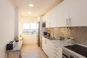 a kitchen with white cabinets and a large window at Sunset entre a Ria e o Teatro in Faro