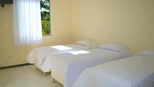 a row of beds in a room with white sheets at Hotel Absolar in Alagoinhas