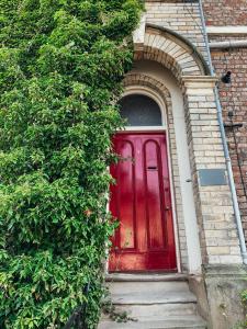 uma porta vermelha num edifício de tijolos com um arco em The Garden Room em York