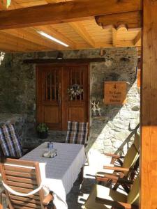 un patio con mesa, sillas y pared de piedra. en To Spiti tou Faliari en Platanistasa