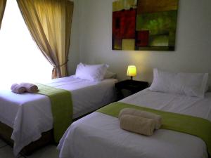 two beds in a hotel room with a window at Sunshine Self Catering in Nelspruit