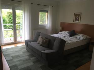 1 dormitorio con cama, sofá y balcón en Luca Apartments, en Zalakaros
