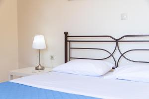 a bedroom with a bed with white pillows and a lamp at Apartments Efi in Artemida