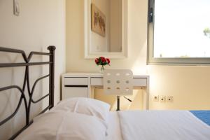 a bedroom with a bed and a desk with a vase of flowers at Apartments Efi in Artemida