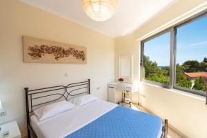 a bedroom with a bed and a large window at Apartments Efi in Artemida