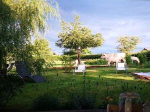 una vaca parada en un patio con sillas y un campo en Gites Luzy Morvan Bourgogne en Luzy