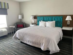 莫纳汉斯Hampton Inn Monahans, Tx的配有一张大床和一把椅子的酒店房间