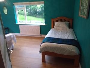 um quarto com uma cama numa parede verde em Ardvonie House em Kingussie
