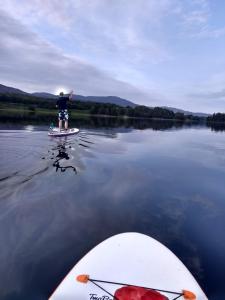 a man standing on a paddle board on a lake at Ardvonie House in Kingussie