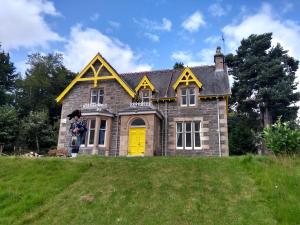 una casa con una porta gialla su una collina di Ardvonie House a Kingussie