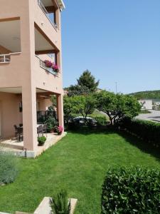 un gran patio frente a un edificio con césped verde en Apartments Nika, en Cavtat