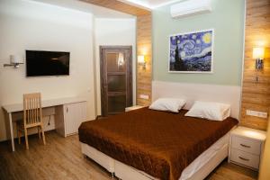 a bedroom with a bed and a desk and a television at Hotel Complex Kupecheskiy Dvor in Rostov on Don