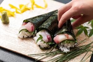 a sushi roll with meat and rice on a cutting board at HOTEL TORIFITO KANAZAWA in Kanazawa