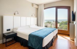 
a hotel room with a large bed and a large window at Ilunion Caleta Park in Sant Feliu de Guíxols
