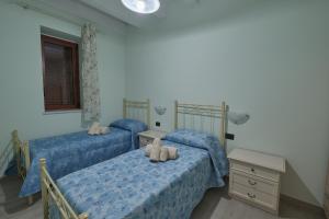 two twin beds in a bedroom with blue sheets at La rosa dei venti, apartment 3 in Porto Empedocle