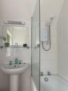 a white bathroom with a sink and a shower at West Lodge Hotel in Aylesbury