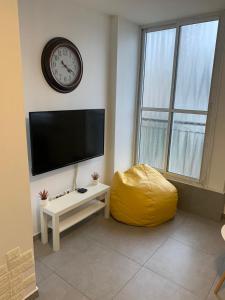 a living room with a flat screen tv and a yellow ottoman at Apartment Harmony in Bat Yam