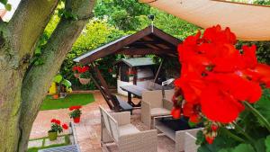 un giardino con gazebo e fiori rossi di Fruzsi Vendégház a Szentbékkálla