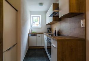 a small kitchen with white cabinets and a sink at Appartementhaus Bergland in Obsteig