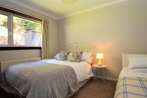 a bedroom with two beds and a window at Nursery Cottage in Kilmun