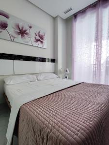 1 dormitorio con 1 cama grande y una pintura en la pared en GEMELOS Levante beach apartments, en Benidorm