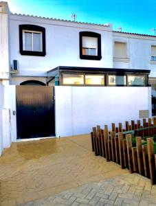 um edifício branco com um portão e algumas cadeiras em Adosado Las Gaviotas Casa completa em Tarifa