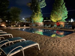 a swimming pool at night with chairs and lights at The Escape Inn in South Yarmouth