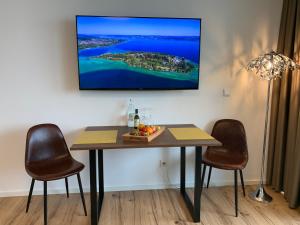 uma mesa de jantar com duas cadeiras e uma televisão na parede em Apartment TraumSeeblick Immenstaad em Immenstaad am Bodensee