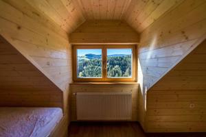 ein Schlafzimmer in einem Holzhaus mit einem Fenster in der Unterkunft Apartmaji na kozolcu - Smogavc in Zreče