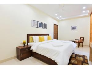 1 dormitorio con 1 cama grande con sábanas blancas y almohadas amarillas en BluO Studio5 Golf Course Road - Gym, Terrace Garden en Gurgaon