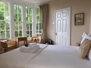 a bedroom with a large white bed with windows at The Charterhouse in Torquay