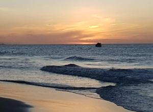 a sunset over the ocean with a boat in the water at MelBliss Gostoso in São Miguel do Gostoso