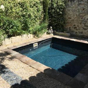une piscine dans un jardin avec un mur en pierre dans l'établissement Chez Marie, à Maillane
