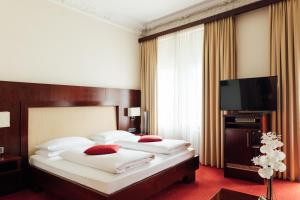 a hotel room with two beds and a flat screen tv at Hotel de France Wiesbaden City in Wiesbaden