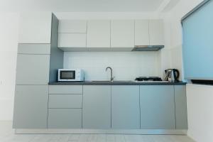 a kitchen with white cabinets and a microwave at Casa Erty in Eforie Nord