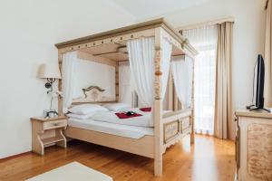 a bedroom with a canopy bed and a television at Hotel de France Wiesbaden City in Wiesbaden