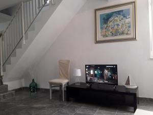 a living room with a tv and a chair and stairs at Apartment More Sumartin in Sumartin