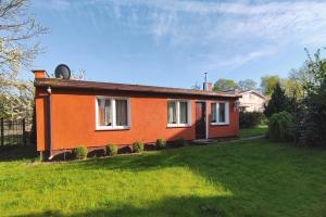 una pequeña casa naranja en un césped verde en Domek u Janiny, en Czaplinek