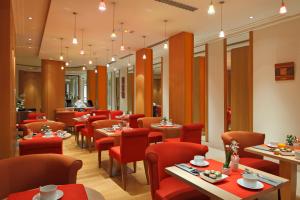 un restaurante con mesas y sillas rojas en una habitación en Westside Arc de Triomphe Hotel, en París