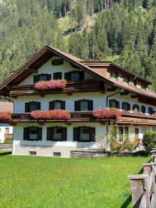 een gebouw met bloemen op de ramen in een veld bij Pension Eberharter in Mayrhofen