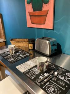 a table with a toaster and two cups on it at Le grand briochin in Saint-Brieuc
