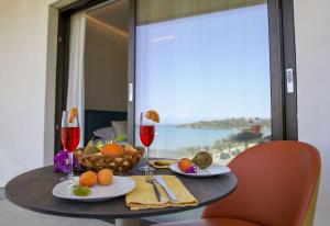 una mesa con un bol de frutas y copas de vino en Sunset Hotel en Cefalú