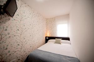 a small bedroom with a bed and a window at Noja Rooms in O Pedrouzo