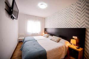 Un dormitorio con una cama grande y un televisor de pantalla plana. en Noja Rooms, en O Pedrouzo