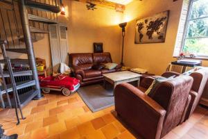 a living room with a leather couch and a table at Longère Touraine Anjou in Hommes +4 photos