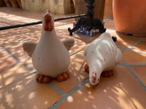 two toy chickens sitting on a tile floor at ROOMQUEO-Only Adults in Barbate