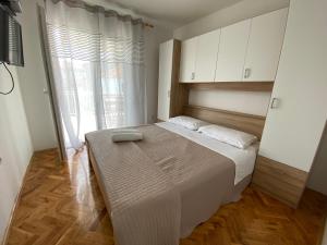 ein Schlafzimmer mit einem großen Bett und einem großen Fenster in der Unterkunft Apartments Roko in Turanj