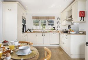 uma cozinha com armários brancos e uma mesa de madeira em Holly Cottage em Ampney Crucis